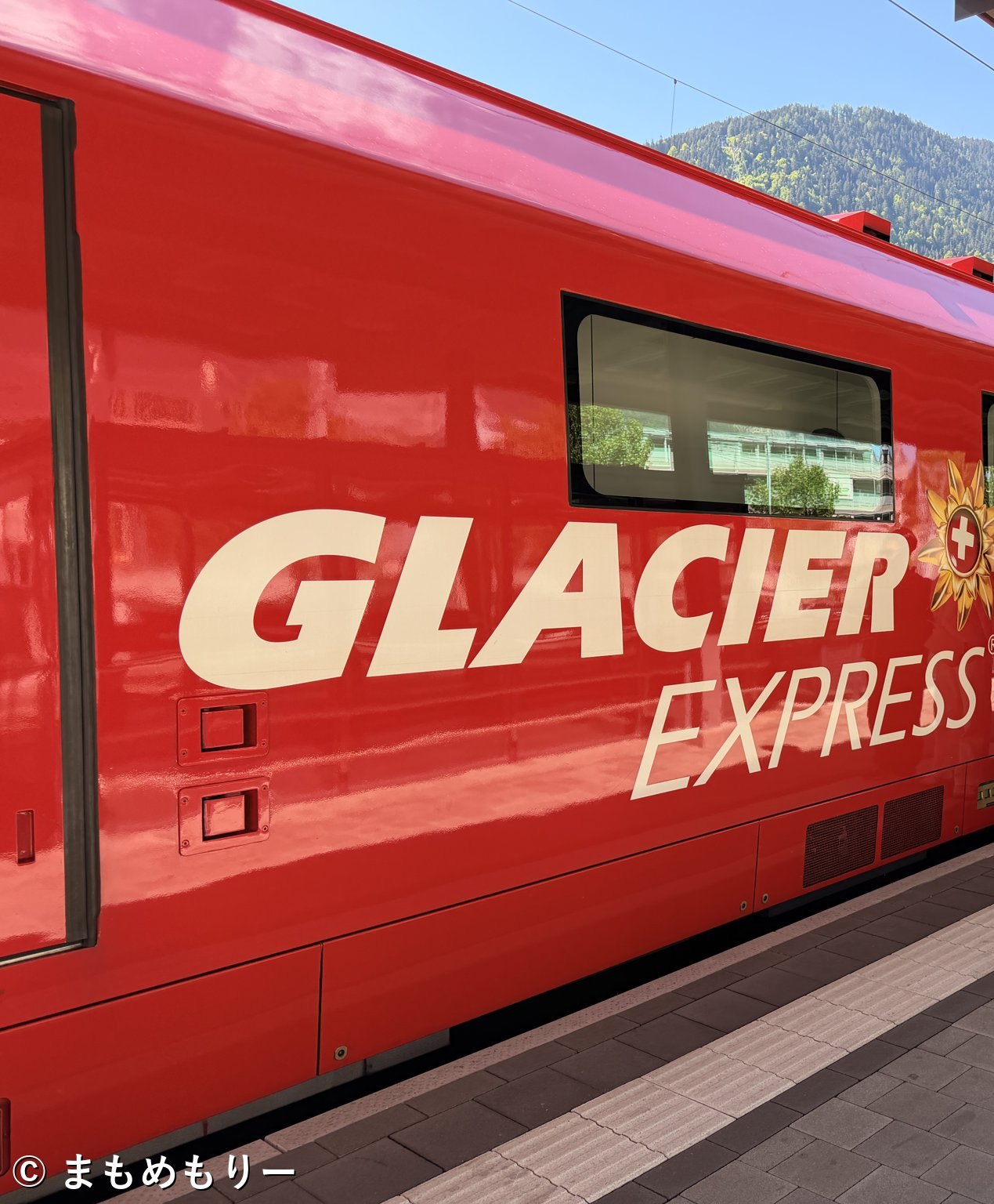 ディセンティス駅に停車する氷河特急の赤い車両とGLACIER EXPRESSのロゴ